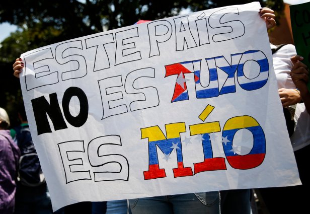 Anti-government protester holds placard depicting Cuban and Venezuelan flags during gathering against Nicolas Maduro's government outside the Embassy of Portugal in Caracas