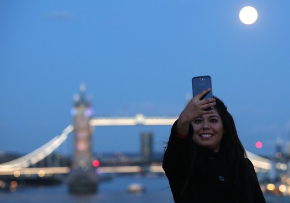 A woman takes a selfie as the supermoon rises over Tower Bridge in London