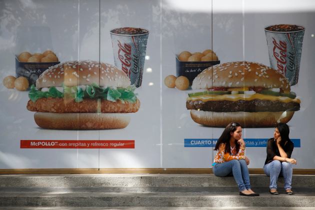 Women chat in front of a McDonald's restaurant in Caracas