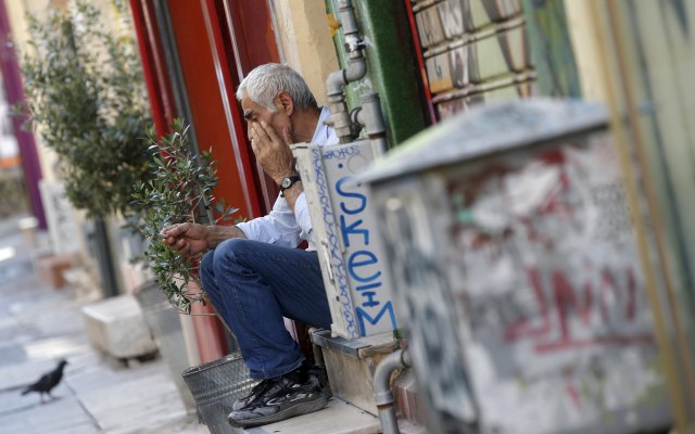 A vendor sits on the steps in front of his shop in central Athens