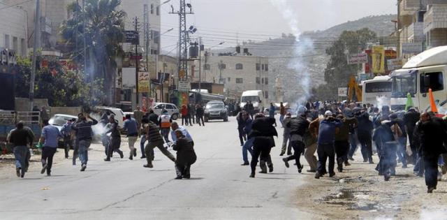  Un grupo de manifestantes palestinos huye de los botes de gas lacrimógeno lanzados por la policía israelí durante una protesta que ha causado disturbios en el "Día de la Tierra", jornada en la que los palestinos protestan por la expropiación de sus tierras, en Howara, cerca de la ciudad de Nablus (Cisjordania) hoy, lunes 30 de marzo de 2015. Distintas localidades árabes del norte y sur de Israel albergarán hoy actos y marchas destinadas a rememorar el 39 aniversario de la muerte en Galilea de seis palestinos con ciudadanía israelí que participaban en una protesta contra la confiscación de sus terrenos y la judaización de la región. EFE/Alaa Badarneh