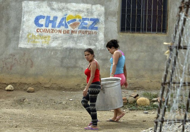 ATENCION ACOMPANA NOTA DE VALENTINA OROPEZA Two women carry a huge pot along a street of "La Invasion" low-income neighborhood in San Antonio, Tachira state, in the border with Colombia on November 28, 2015.  AFP  PHOTO/GEORGE CASTELLANOS / AFP / George CASTELLANOS