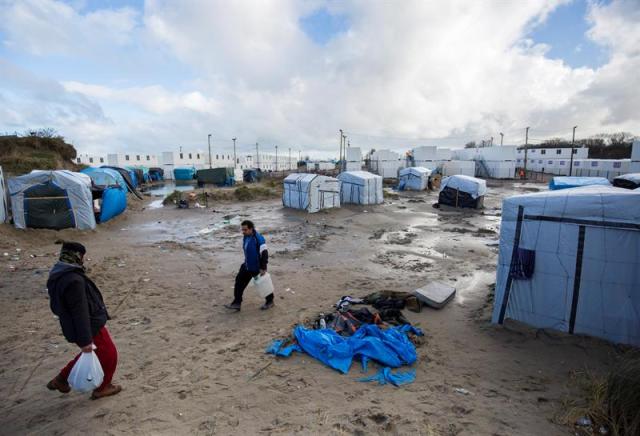 Varios inmigrantes caminan entre las tiendas de campaña y chabolas en el campamento llamado "La jungla" montado cerca de una zona vallada con contenedores utilizados como alojamientos en Calais (Francia) hoy, 15 de febrero de 2016. El Gobierno galo puso una semana como la nueva fecha límite para el desmantelamiento de los asentamientos de inmigrantes, ya que las autoridades planean crear una zona de exclusión de peronas para controlar mejor a los inmigrantes que intentan esconderse en camiones para poder llegar al Reino Unido. Entre 4.000 y 7.000 inmigrantes viven actualmente en "La Jungla". EFE/Julien Warnand