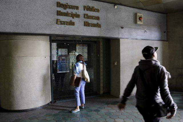 A woman stands in front of a closed public registry office in Caracas, April 8, 2016. REUTERS/Marco Bello