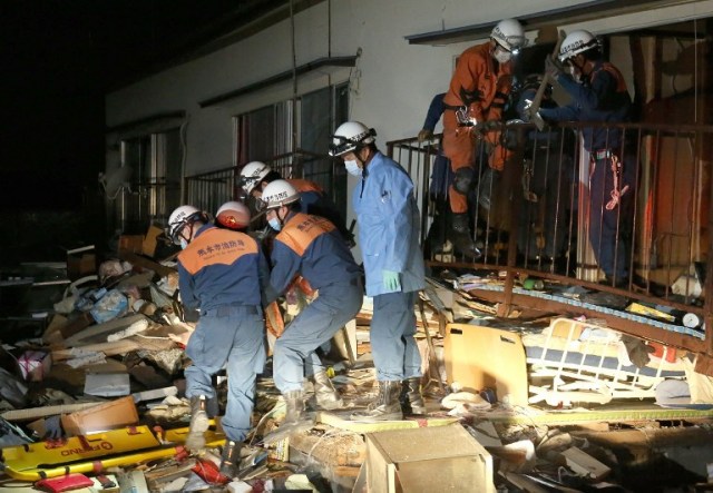 Rescue workers save a person from a collaspsed building in Kuammoto on April 16, 2016. A more powerful quake hit southern Japan, killing at least seven people, toppling large buildings and triggering a massive landslide just over a day after an earlier tremor which left nine dead. / AFP PHOTO / JIJI PRESS / JIJI PRESS / Japan OUT