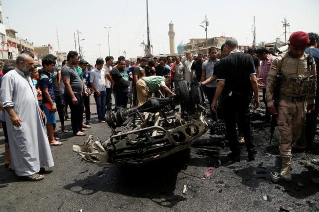 Un grupo de personas se reúnen en la escena de la explosión de un coche bomba, en Bagdad, Irak. Tres ataques suicidas con bombas reivindicados por Estado Islámico en Bagdad causaron la muerte de al menos 80 personas el miércoles, dijeron la policía iraquí y fuentes hospitalarias, en los atentados más mortales del año en la capital. 11 de mayo de 2016. REUTERS/Wissm al-Okili