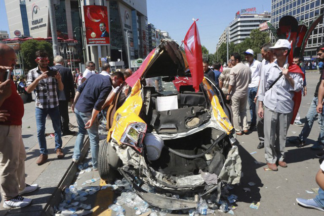 People look at a destroyed car as they march from Kizilay square towards the Turkish General Staff building in Ankara, on July 16, 2016, following a failed coup attempt. Turkish authorities said they had regained control of the country on July 16 after thwarting a coup attempt by discontented soldiers to seize power from President Recep Tayyip Erdogan that claimed more than 250 lives. / AFP PHOTO / ADEM ALTAN