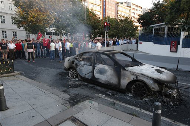TUrcos reunidos ante un auto quemado en Estambul, el sábado 16 de julio de 2016. El presidente de Turquía, Recep Tayyip Erdogan, declaró el sábado de madrugada que tenía el control del país tras un intento de golpe de Estado. (AP Foto/Emrah Gurel)