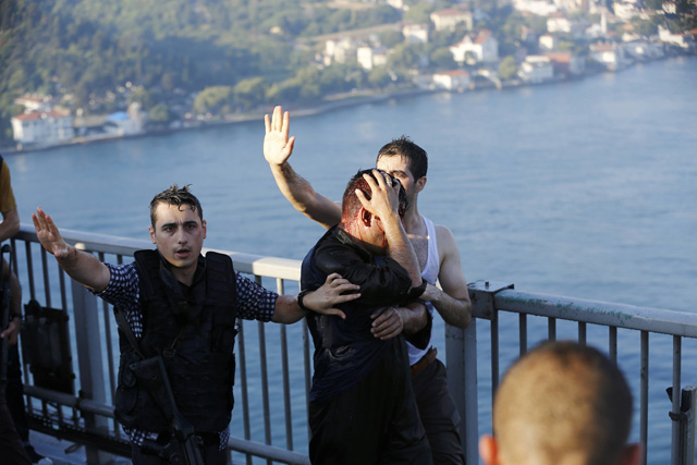 Policemen protect a soldier from the mob after troops involved in the coup surrendered on the Bosphorus Bridge in Istanbul, Turkey July 16, 2016. REUTERS/Murad Sezer