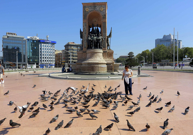 A woman feeds pigeons in front of the Republic Monument at Taksim Square in Istanbul after an attempted coup in Turkey, July 16, 2016. REUTERS/Kemal Aslan