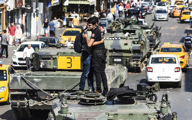 Turkish police officer (R) embrace a man on a tank after the military position was taken over at the Anatolian side at Uskudar in Istanbul on July 16, 2016. President Recep Tayyip Erdogan urged Turks to remain on the streets on July 16, 2016, as his forces regained control after a spectacular coup bid by discontented soldiers that claimed more than 250 lives. Describing the attempted coup as a "black stain" on Turkey's democracy, Yildirim said that 161 people had been killed in the night of violence and 1,440 wounded. / AFP PHOTO / BULENT KILIC