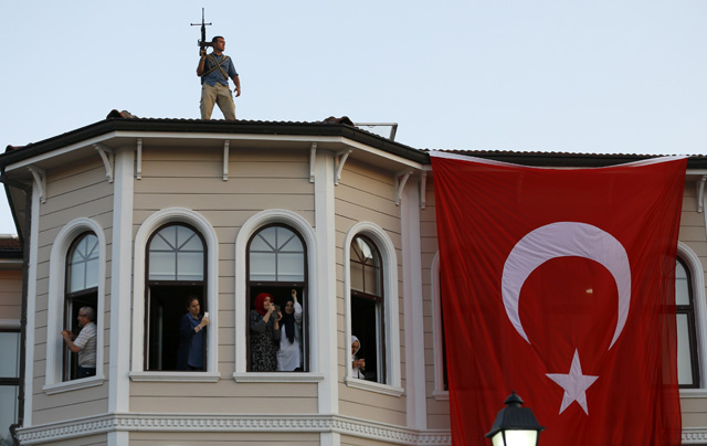 People try to take pictures of Turkish President Tayyip Erdogan walking through the crowd of supporters, as a security officer stands on the roof in Istanbul, Turkey, July 16, 2016. REUTERS/Murad Sezer