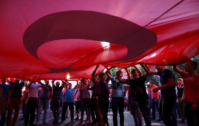 Supporters of Turkish President Tayyip Erdogan hold a giant Turkish flag during a demonstration outside parliament building in Ankara, Turkey, July 16, 2016. REUTERS/Osman Orsal TPX IMAGES OF THE DAY