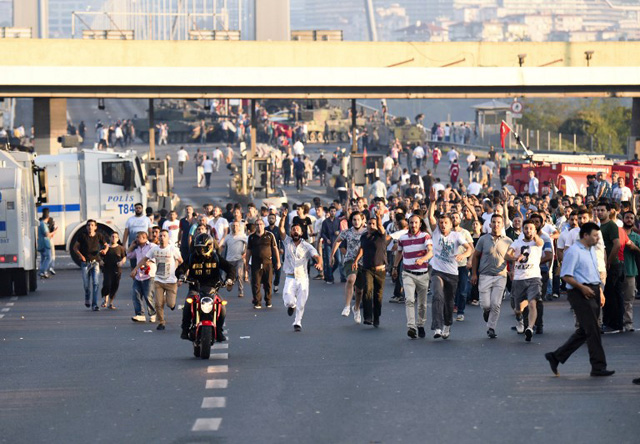 People run away from tanks after taking over military position on the Bosphorus bridge in Istanbul on July 16, 2016, following an attempt by discontented soldiers to seize power from President Recep Tayyip Erdogan that claimed more than 250 lives. After the bloodiest challenge to his 13-year autocratic rule, Erdogan urged his backers to stay on the streets to prevent a possible "flare-up" of yesterday's chaos in the strategic NATO member of 80 million people. / AFP PHOTO / BULENT KILIC