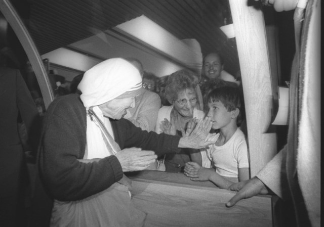 Foto de archivo de la Madre Teresa de Calcuta saludando a un niño que estaba entre los cientos de personas que fueron a recibirla en el Aeropuerto de Quebec, Canadá. 10 de junio de 1986. La canonización de la Madre Teresa de Calcuta el domingo será la culminación de un proceso -a veces llamado "la máquina de hacer santos"- que es largo, complejo, caro, poco claro y con frecuencia polémico. Reuters/Jacques Boissinot