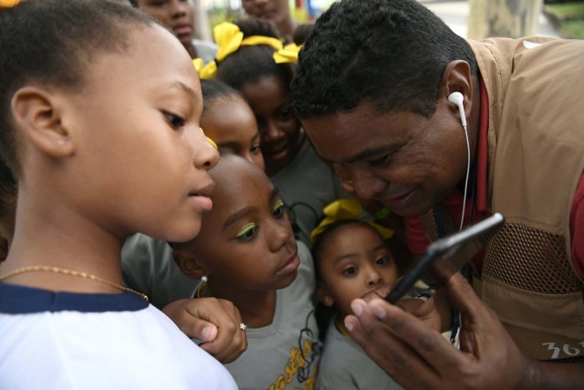 Blind Brazilian photographer Joao Maia explains to some children how he takesc pictures with his smartphone using the sound as a reference during the Rio 2016 Paralympic Games in Rio de Janeiro, Brazil on September 9, 2016. 41-year-old Maia lost his sight at age 28 due to an affection of the uvea. This is the first sportive event y covers as a photographer. / AFP PHOTO / CHRISTOPHE SIMON