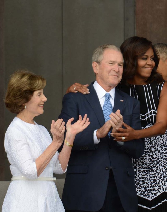 WASHINGTON, DC - SEPTEMBER 24: First lady Michelle Obama, embraces former president George W. Bush, accompanied by his wife, former first lady Laura Bush, while participating in the dedication of the National Museum of African American History and Culture September 24, 2016 in Washington, DC, before the museum opens to the public later that day. The museum is a Smithsonian Institution museum located on the National Mall featuring African American history and culture in the US. Astrid Riecken/Getty Images/AFP