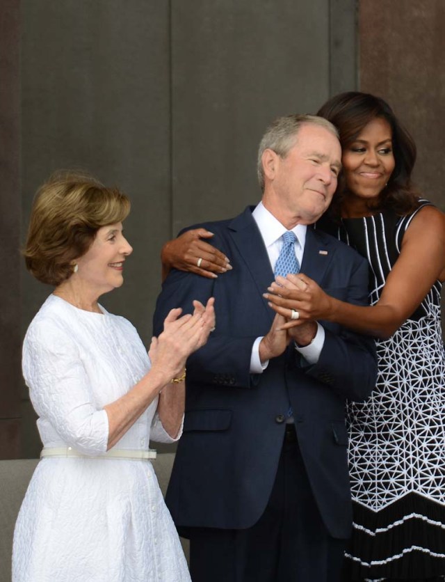 WASHINGTON, DC - SEPTEMBER 24: First lady Michelle Obama, embraces former president George Bush, accompanied by his wife, former first lady Laura Bush, while participating in the dedication of the National Museum of African American History and Culture September 24, 2016 in Washington, DC, before the museum opens to the public later that day. The museum is a Smithsonian Institution museum located on the National Mall featuring African American history and culture in the US. Astrid Riecken/Getty Images/AFP