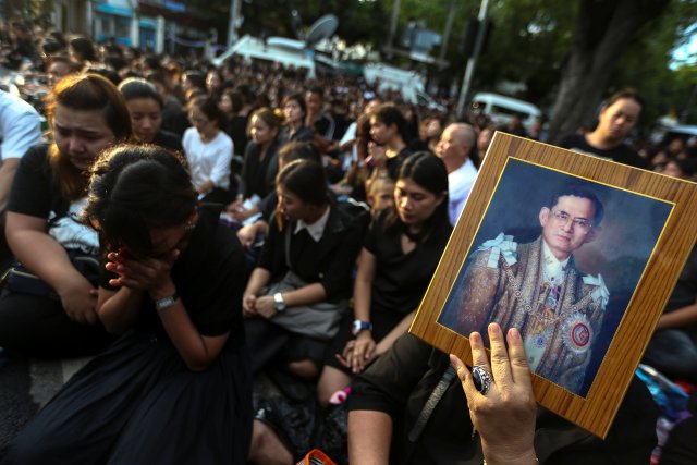 Mourners pray as a woman holds up a portrait of Thailand's King Bhumibol Adulyadej while his body is being moved from the Bangkok hospital where he died to the Grand Palace, in Bangkok, Thailand, October 14, 2016. REUTERS/Athit Perawongmetha