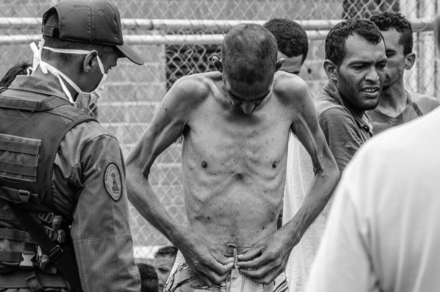 Jerson Ronarcho se desviste para la requisa de la Guardia Nacional. Todas sus pertenencias las lleva puestas: dos franelas, ropa interior, bermudas, pantalón y zapatos croccs . Al quitarse la ropa se deja ver el estado de desnutrición en que se encuentra Foto: Carlos Hernández