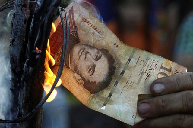 Un hombre quema un billete de 100 bolívares durante una protesta en El Pinal, Venezuela. 16 diciembre 2016. Cientos de venezolanos cruzaron la mañana del sábado uno de los pasos fronterizos hacia Colombia, en protesta por la falta de efectivo en su país y desafiando la orden del presidente Nicolás Maduro de mantener cerrado el acceso al territorio por vía terrestre hasta el domingo. REUTERS/Carlos Eduardo Ramírez