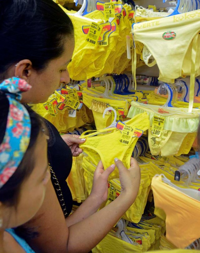 A customer looks at yellow underwear for sell at a store in Medellin, Colombia, on December 29, 2016, where tradition holds that it brings prosperity and good luck if you wear it on New Year's Eve. / AFP PHOTO / CAMILO GIL