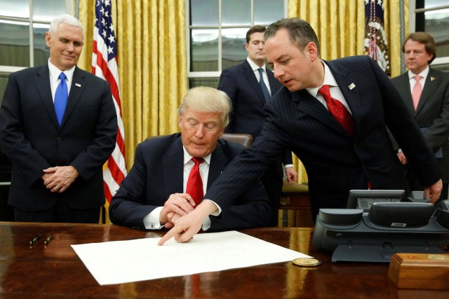 White House Chief of Staff Reince Priebus (R) directs U.S. President Donald Trump, flanked by Vice President Mike Pence (L), where to sign the document to confirming James Mattis his Secretary of Defense, his first signing in the Oval Office in Washington, U.S. January 20, 2017. REUTERS/Jonathan Ernst