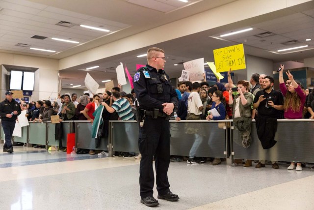 Police maintain walkways as people gather to protest against the travel ban imposed by U.S. President Donald Trump's executive order, at Dallas/Fort Worth International Airport in Dallas, Texas, U.S. January 28, 2017. REUTERS/Laura Buckman