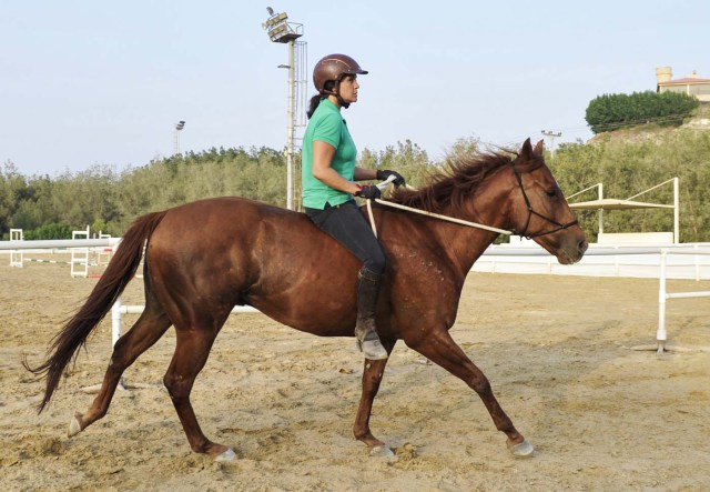 Saudi Dana al-Gosaibi trains a horse on March 1, 2017, in the Red Sea city of Jeddah. The 35-year-old Saudi horse trainer dreams of opening her own stables to focus on "a more gentle" way of training horses than the standard approach in the male-dominated kingdom. / AFP PHOTO / Amer HILABI