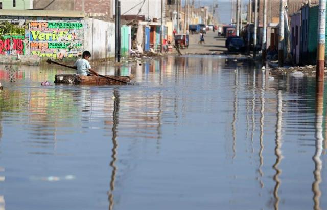 Un niño damnificado del pueblo de Huarmey, se desplaza sobre una pequeña balsa hoy, miércoles 22 de marzo del 2017, por una calle inundada de la ciudad de Huarmey en la región costera de Ancash (Perú). Huarmey ha sido una de las ciudades mas golpeadas por las inundaciones producidas por el fenómeno climático llamado "niño costero". EFE / Ernesto Arias