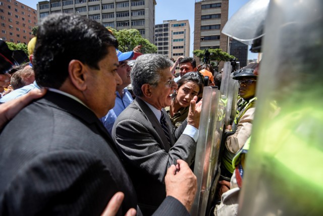 Former President of the Venezuelan National Assembly Henry Ramos Allup(C) speaks with riot police officers during a protest against Nicolas Maduro's government in Caracas on April 4, 2017. Protesters clashed with police in Venezuela Tuesday as the opposition mobilized against moves to tighten President Nicolas Maduro's grip on power. Protesters hurled stones at riot police who fired tear gas as they blocked the demonstrators from advancing through central Caracas, where pro-government activists were also planning to march.  / AFP PHOTO / JUAN BARRETO