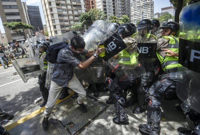 Venezuela's opposition activists clash with riot police agents during a protest against Nicolas Maduro's government in Caracas on April 4, 2017. Protesters clashed with police in Venezuela Tuesday as the opposition mobilized against moves to tighten President Nicolas Maduro's grip on power. Protesters hurled stones at riot police who fired tear gas as they blocked the demonstrators from advancing through central Caracas, where pro-government activists were also planning to march.  / AFP PHOTO / JUAN BARRETO