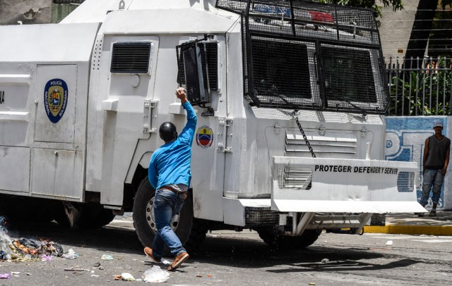 A Venezuela's opposition activist hits a Bolivarian police armored truck with a stone, during a protest against Nicolas Maduro's government in Caracas on April 4, 2017. Protesters clashed with police in Venezuela Tuesday as the opposition mobilized against moves to tighten President Nicolas Maduro's grip on power. Protesters hurled stones at riot police who fired tear gas as they blocked the demonstrators from advancing through central Caracas, where pro-government activists were also planning to march.  / AFP PHOTO / JUAN BARRETO