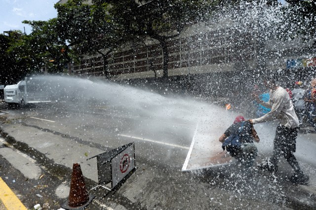 A riot police water cannon sprays demonstrators during a protest against President Nicolas Maduro's government in Caracas on April 4, 2017.  Activists clashed with police in Venezuela Tuesday as the opposition mobilized against moves to tighten President Nicolas Maduro's grip on power. Protesters hurled stones at riot police who fired tear gas as they blocked the demonstrators from advancing through central Caracas, where pro-government activists were also planning to march. / AFP PHOTO / FEDERICO PARRA