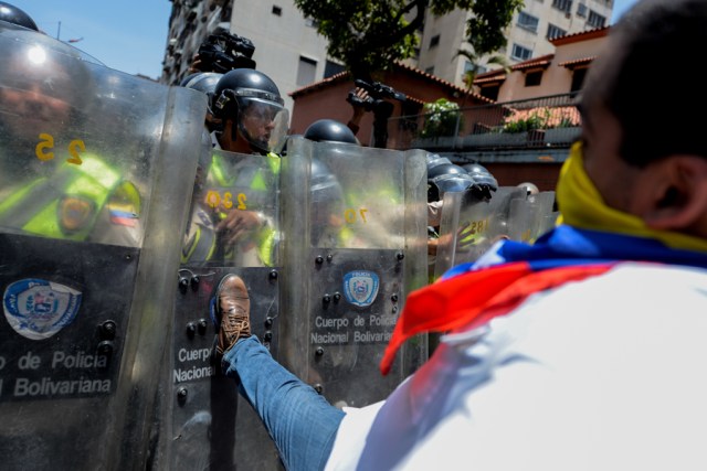 Demonstrators scuffle with riot police during a protest against President Nicolas Maduro's government in Caracas on April 4, 2017.  Activists clashed with police in Venezuela Tuesday as the opposition mobilized against moves to tighten President Nicolas Maduro's grip on power. Protesters hurled stones at riot police who fired tear gas as they blocked the demonstrators from advancing through central Caracas, where pro-government activists were also planning to march. / AFP PHOTO / FEDERICO PARRA