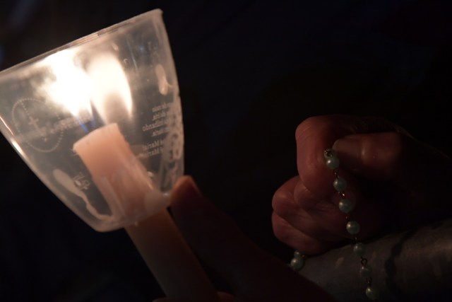A pilgrim holds a candle and a rosary at the Shrine of Fatima during the Blessing for the Candles from the Chapel of the Apparitions by Pope Francis, in Fatima on May 12, 2017. Two of the three child shepherds who reported apparitions of the Virgin Mary in Fatima, Portugal, one century ago, will be declared saints on May 13, 2017 by Pope Francis. The canonisation of Jacinta and Francisco Marto will take place during the Argentinian pontiff's visit to a Catholic shrine visited by millions of pilgrims every year. / AFP PHOTO / Tiziana FABI