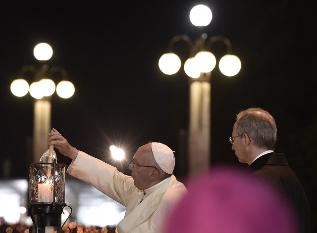 Pope Francis (L) lights a candle during the Blessing for the Candles from the Chapel of the Apparitions, in Fatima on May 12, 2017. Two of the three child shepherds who reported apparitions of the Virgin Mary in Fatima, Portugal, one century ago, will be declared saints on May 13, 2017 by Pope Francis. The canonisation of Jacinta and Francisco Marto will take place during the Argentinian pontiff's visit to a Catholic shrine visited by millions of pilgrims every year. / AFP PHOTO / TIZIANA FABI