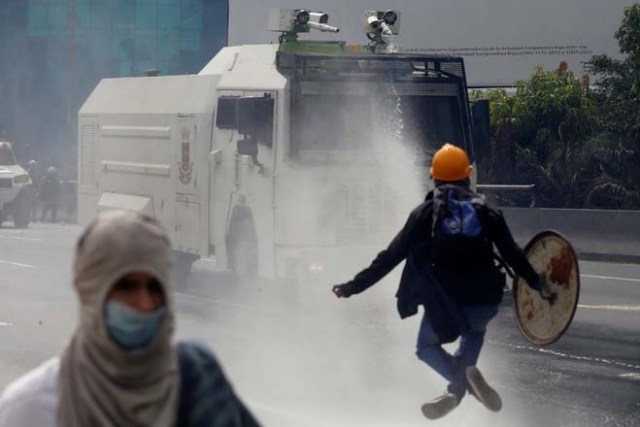 A demonstrator jumps as he confronts a police water cannon vehicle during a rally called by health care workers and opposition activists against Venezuela's President Nicolas Maduro in Caracas, Venezuela May 22, 2017. REUTERS/Marco Bello