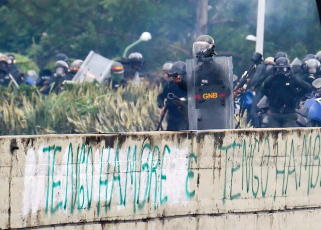 A member of the National Guard holds a gun during clashes with opposition activists demonstrating against the government of President Nicolas Maduro along the Francisco Fajardo highway in Caracas on June 19, 2017. Near-daily protests against President Nicolas Maduro began on April 1, with demonstrators demanding his removal and the holding of new elections. The demonstrations have often turned violent with 73 people killed and more than 1,000 injured so far, prosecutors say, and more than 3,000 arrested, according to the NGO Forum Penal. / AFP PHOTO / Juan BARRETO