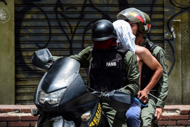 National Guard motorcyclists take an arrested demonstrator into custody during an anti-government protest in Caracas, on July 20, 2017. A 24-hour nationwide strike got underway in Venezuela Thursday, in a bid by the opposition to increase pressure on beleaguered leftist President Nicolas Maduro following four months of deadly street demonstrations. / AFP PHOTO / RONALDO SCHEMIDT