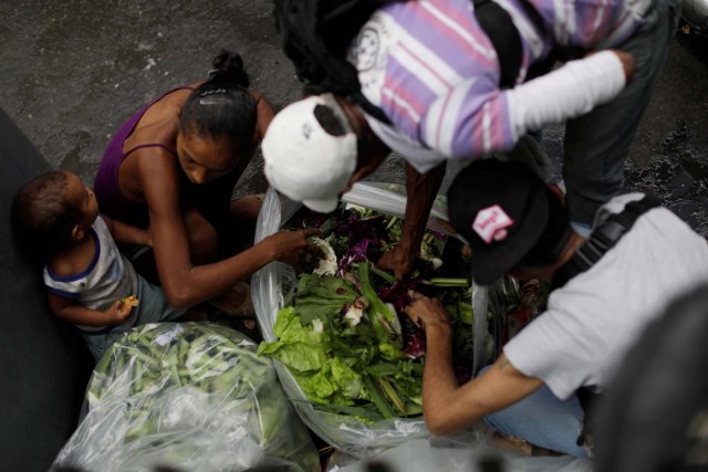 People search for food in garbage bags next to a supermarket in Caracas, Venezuela, July 25, 2017. REUTERS/Ueslei Marcelino