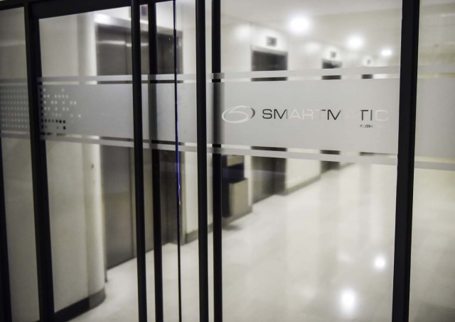 Picture of the logo of Smartmatic, the firm that supplies Venezuela's voting technology, seen on a sliding door at the headquarters of the company in Caracas, on August 2, 2017. Smartmatic said official figures in Sunday's election of the new super-assembly, with candidates selected from the ruling party, were "tampered with" in such a way that the turnout appeared greater than it was. Venezuela's President Nicolas Maduro moved quickly Wednesday to swear in a new assembly with extraordinary powers as he faced charges that turnout figures for the body's election were "manipulated." / AFP PHOTO / Ronaldo SCHEMIDT