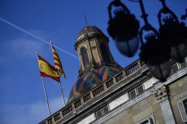 Las banderas española (L) y catalana Senyera revolotean sobre el Palacio de la Generalitat de Cataluña en Barcelona el 28 de octubre de 2017, un día después de que se impuso el control directo sobre la región en un intento por separarse de España. España se movió para afirmar el dominio directo sobre Cataluña, reemplazando a sus funcionarios ejecutivos y altos para sofocar un impulso de independencia que ha sumido al país en una crisis y ha puesto nerviosa a la Europa secesionista. / AFP PHOTO / PIERRE-PHILIPPE MARCOU