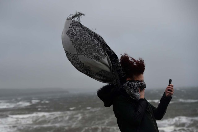 A woman takes a picture during storm Ophelia in the County Clare town of Lahinch, Ireland October 16, 2017. REUTERS/Clodagh Kilcoyne