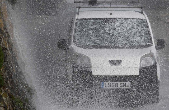 A car is driven as large waves crash along sea defences and the harbour as storm Ophelia approaches Porthleven in Cornwall, south west Britain, October 16, 2017. REUTERS/Toby Melville