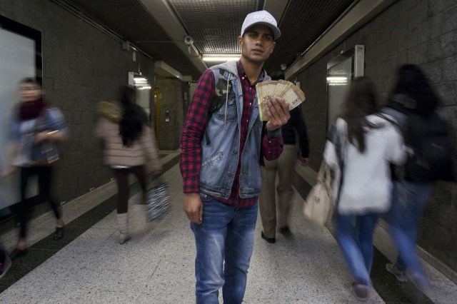 Venezuelan national Jhonger Pina, 25, shows Bolivar bills as a curiosity in exchange for local coins, at a bus station in Bogota, on October 26, 2017. Up to October 2017 there were 470,000 Venezuelans in Colombia, who left their country to escape the hardship and violence of its economic and political crisis. / AFP PHOTO / Raul Arboleda / TO GO WITH AFP STORY by Daniela QUINTERO and Santiago TORRADO