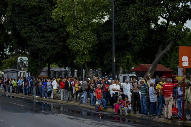 People queue at a bus stop in Catia, a neighbourhood of Caracas, on November 1, 2017. People queue for upto four hours to take a bus home in Venezuela, where mobilizing by land or plane has become a headache. / AFP PHOTO / Federico PARRA