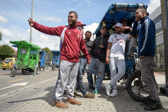 Venezuelan national Gregory Pacheco (R), 29, speaks with his compatriots before starting his working day as a "bicitaxi" (pedicab) driver in Bogota, on November 8, 2017. Up to October 2017 there were 470,000 Venezuelans in Colombia, who left their country to escape the hardship and violence of its economic and political crisis. / AFP PHOTO / Raul Arboleda / TO GO WITH AFP STORY by Daniela QUINTERO and Santiago TORRADO