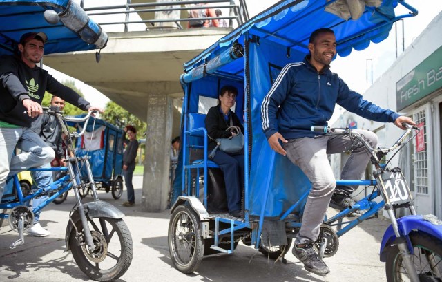 Venezuelan national Gregory Pacheco (R), 29, works as a "bicitaxi" (pedicab) driver in Bogota, on November 8, 2017. Up to October 2017 there were 470,000 Venezuelans in Colombia, who left their country to escape the hardship and violence of its economic and political crisis. / AFP PHOTO / Raul Arboleda / TO GO WITH AFP STORY by Daniela QUINTERO and Santiago TORRADO