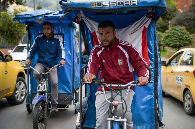 Venezuelan national Gregory Pacheco (L), 29, works as a "bicitaxi" (pedicab) driver in Bogota, on November 8, 2017. Up to October 2017 there were 470,000 Venezuelans in Colombia, who left their country to escape the hardship and violence of its economic and political crisis. / AFP PHOTO / Raul Arboleda / TO GO WITH AFP STORY by Daniela QUINTERO and Santiago TORRADO